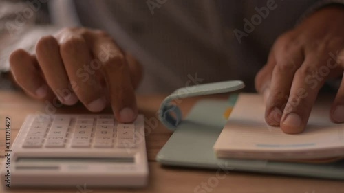 Close up hands of man calculating expenses on the desk. Finances, investment, economy, saving money or insurance concept. photo