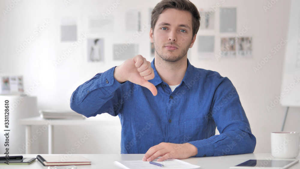 Thumbs Down by Casual Adult Man Sitting at Workplace