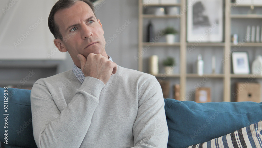Middle Aged Man Thinking New Idea while Sitting on Couch in Creative Office Middle Aged Man Thinking New Idea while Sitting on Couch in Creative Office