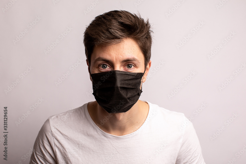 studio shot of a young man wearing a black mask, looking at camera, isolated on white background studio shot of a young man wearing a black mask, looking at camera, isolated on white background