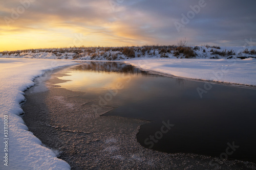 icy banks of a small river at sunset © smolskyevgeny