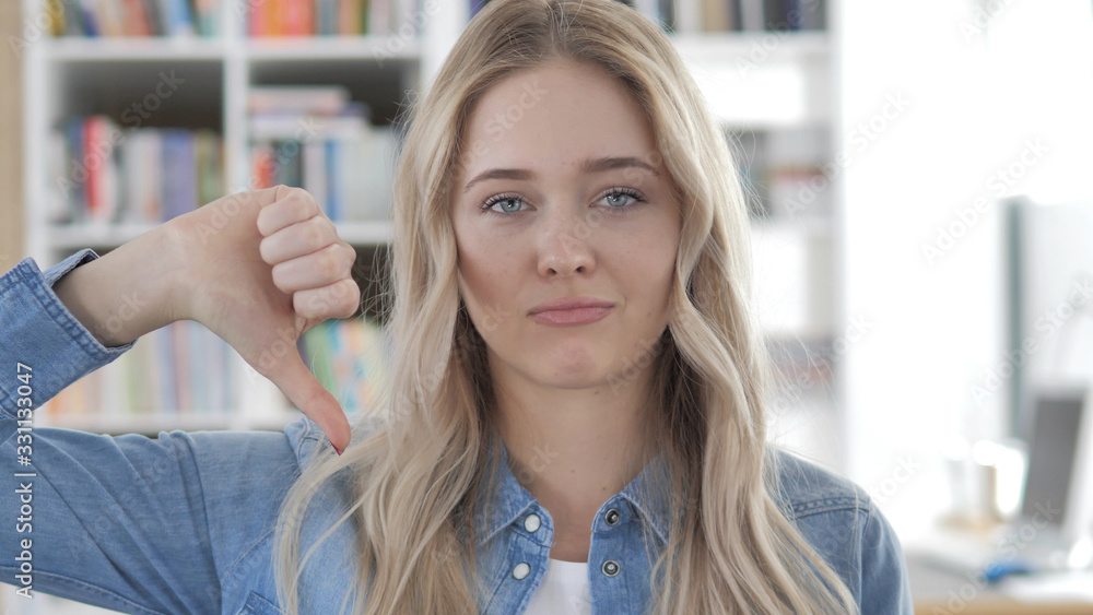 Thumbs Down by Young Blonde Woman in Office