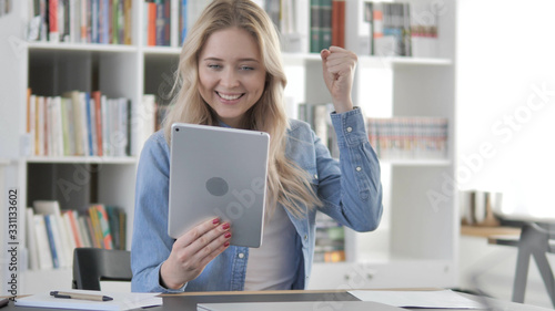 Young Blonde Woman Celebrating Success of Project on Tablet
