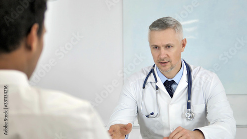 Grey Hair Doctor Telling Patient about Health Conditon and treatment Plan