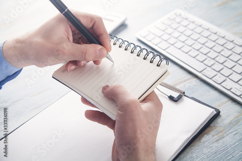 Businessman writing on notepad in business desk.