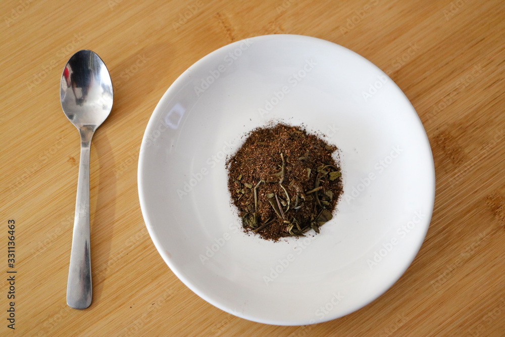 dry tea leaves and green tea powder on the white dish