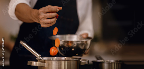 Chef Cooking Food in the Modern Kitchen. Closeup and Selective focus on Hand. Adding Ingredient into the Pot. Male Making Meal