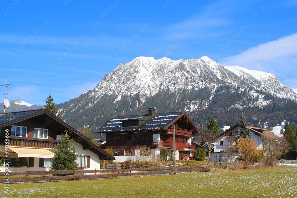 View at traditional Bavarian residential homes in front of snow covered mountains in a ski resort (Oberstdorf, Germany)