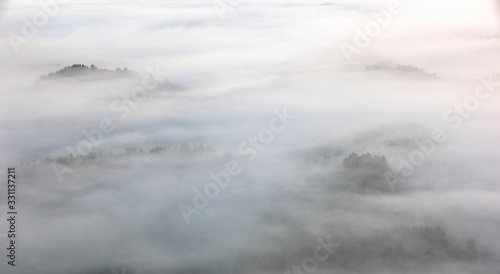 Fog with island hill, misty morning. Hills and villages with foggy morning. Morning fall valley of Bohemian Switzerland park. Hills with fog, landscape of Czech Republic. Clouds in autumn nature.
