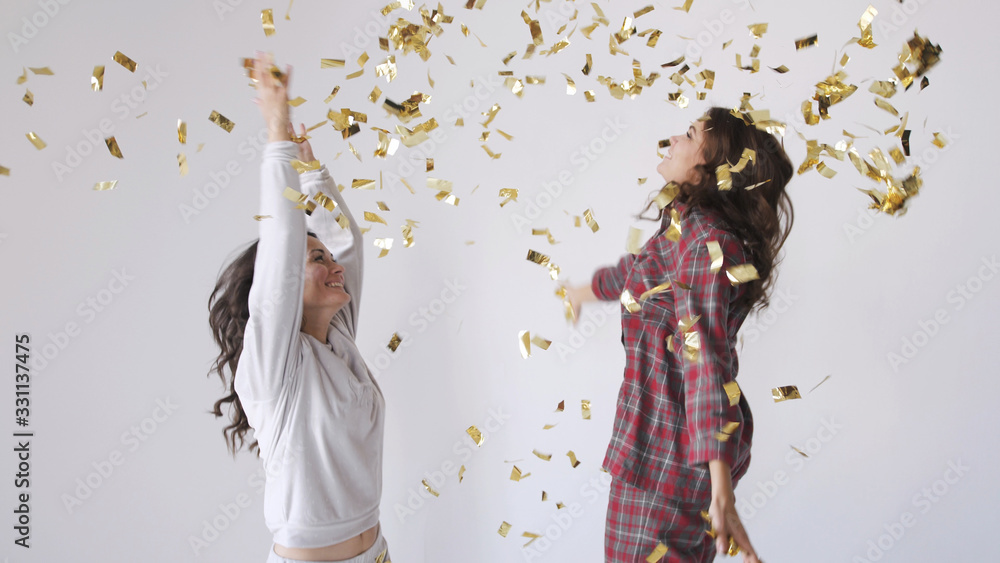 Obraz premium Beautiful happy women throwing gold glitter confetti on a white background