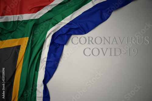 waving national flag of south africa on a gray background with text coronavirus covid-19 . concept.