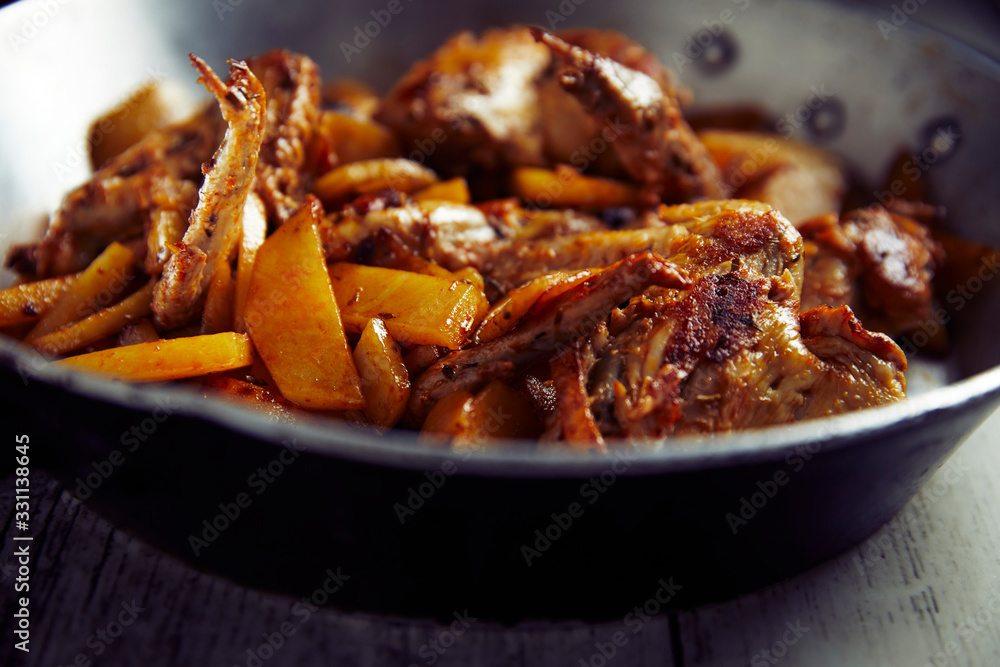 Spicy chicken wings with curry and potatoes, into a iron pot, wood background, close up Spicy chicken wings with curry and potatoes, into a iron pot, wood background, close up