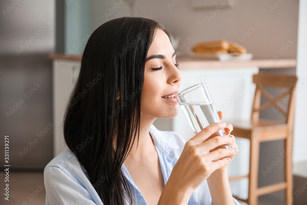 Beautiful young woman drinking water in kitchen Beautiful young woman drinking water in kitchen