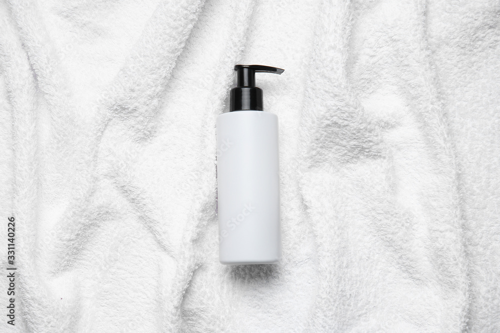 Bottle of shampoo on white towel - obrazy, fototapety, plakaty 
