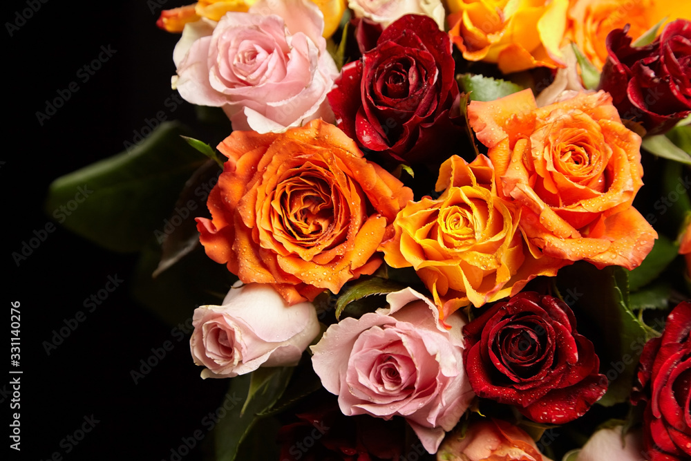 Bouquet of different color roses with water drops on petals on a black background. Red, orange and pink flowers. Romantic Valentine's Day Gift Bouquet of different color roses with water drops on petals on a black background. Red, orange and pink flowers. Romantic Valentine's Day Gift