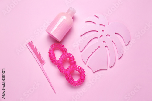 Composition with shampoo, hair ties and comb on color background