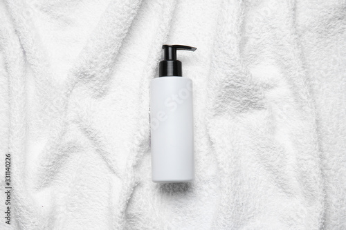 Bottle of shampoo on white towel