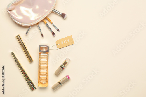 Bottle of perfume with makeup cosmetics and bag on light background