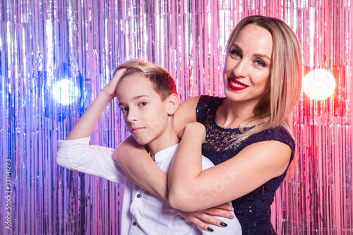 Mothers day, children and family concept - teen boy hugging his mom on shiny party background. © satura_