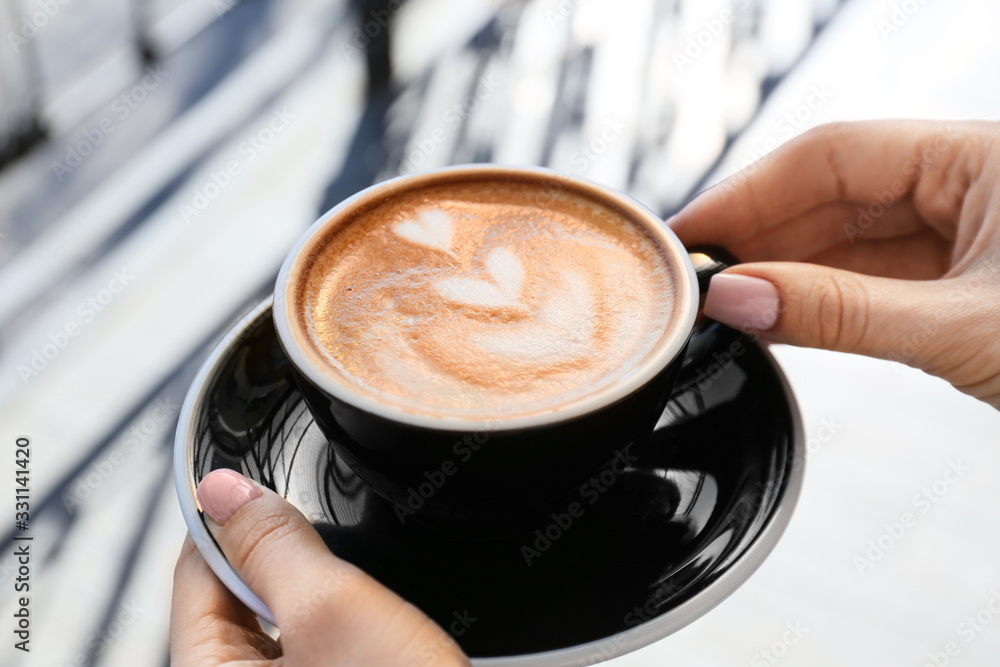 Woman with cup of tasty cappuccino outdoors, closeup Woman with cup of tasty cappuccino outdoors, closeup