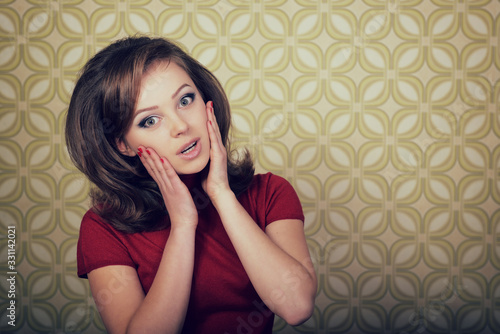 Young smiling ecstatic woman looking at camera in room with vintage wallpaper, retro stylization 60-70s. photo