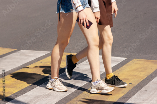 legs of young pedestrians walking on the crosswalk