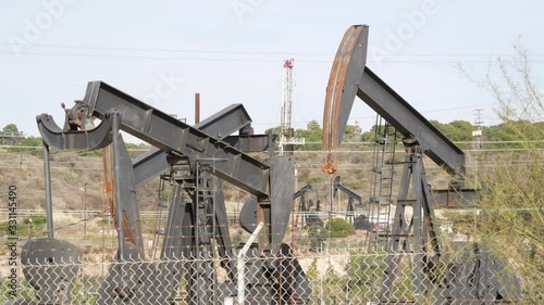 Industrial urban landscape. La Brea Inglewood in Los Angeles. Well pump jack operating behind the fence. Drilling rig extract crude oil. Oil mining machine with working piston. Oil and gas industry.