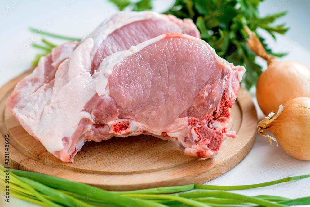 Raw pork chops, parsley, chives and onions. On a cutting board. Ready for cooking Raw pork chops, parsley, chives and onions. On a cutting board. Ready for cooking