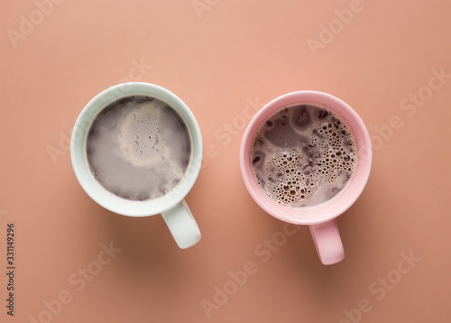 two cups of coffee with milk of pink and mint color on a brown background. view from above photo