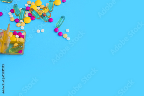 Spilled colored medications and pills on a blue background. Pharmacology and medicine struggle for health.