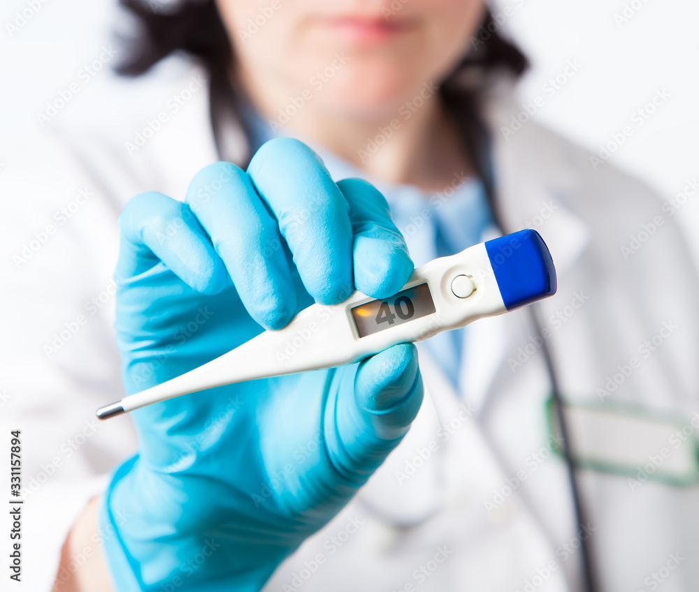 Female doctor holds a electronic thermometer for measuring temperature, closeup. nurse measures the temperature. Shallow depth of field with focus on Female doctor holds a electronic thermometer for measuring temperature, closeup. nurse measures the temperature. Shallow depth of field with focus on