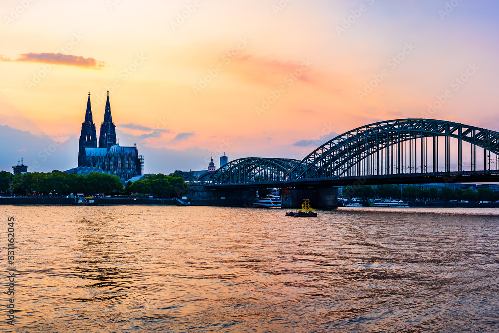 Sunset silhouette skyline landscape of the gothic Cologne Cathedra, Hohenzollern railway and pedestrian bridge, the old town and Great St Martin church on the banks of river Rhine in Cologne, Germany