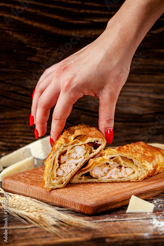 Baking Georgian cuisine. Puff pastry pie with chicken and cheese. The dish lies on a wooden table. background image, copy space text