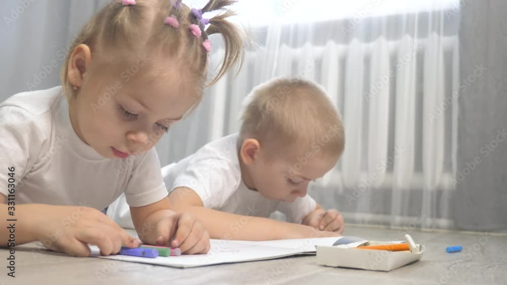 happy family brother and sister teamwork concept. little boy and girl draw on floor in a sketchbook. brother and sister in the room lifestyle draw with crayons happy family brother and sister teamwork concept. little boy and girl draw on floor in a sketchbook. brother and sister in the room lifestyle draw with crayons