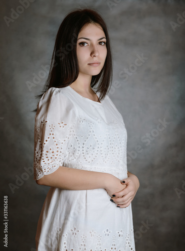 Portrait of a beautiful young brunette in whitee dress. photo