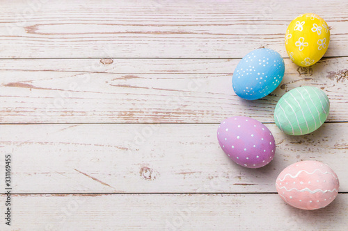 easter background with hand painted pastel colors eggs on light colored wooden table