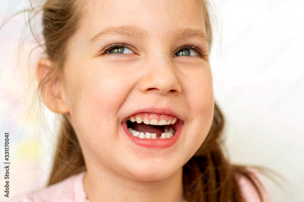 a happy girl in a pink school- age t-shirt without a front tooth laughs. To close. Diphyodont. Isolated on a white background. health a happy girl in a pink school- age t-shirt without a front tooth laughs. To close. Diphyodont. Isolated on a white background. health