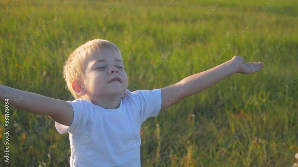 small child hands drawn to heaven concept happy family religion. little boy closed his eyes spread his arms to the sides on the nature in the park at sunset lifestyle slow motion video small child hands drawn to heaven concept happy family religion. little boy closed his eyes spread his arms to the sides on the nature in the park at sunset lifestyle slow motion video