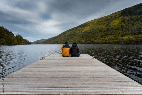 Couple sitting together at the end of a quay gazing the landscape