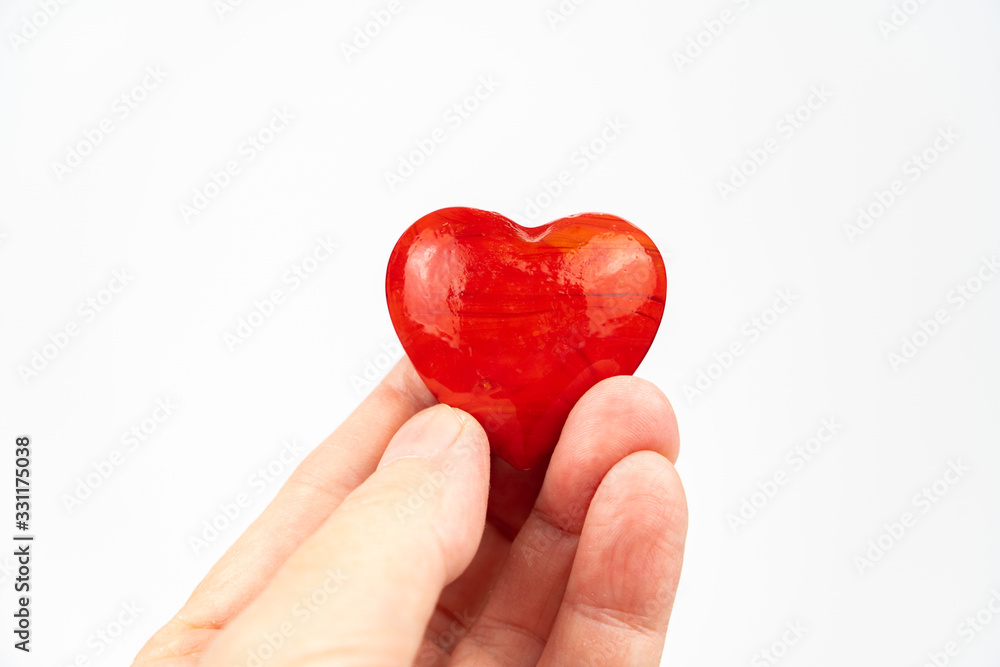 Fototapeta premium Red heart held in hand, white background and copy space