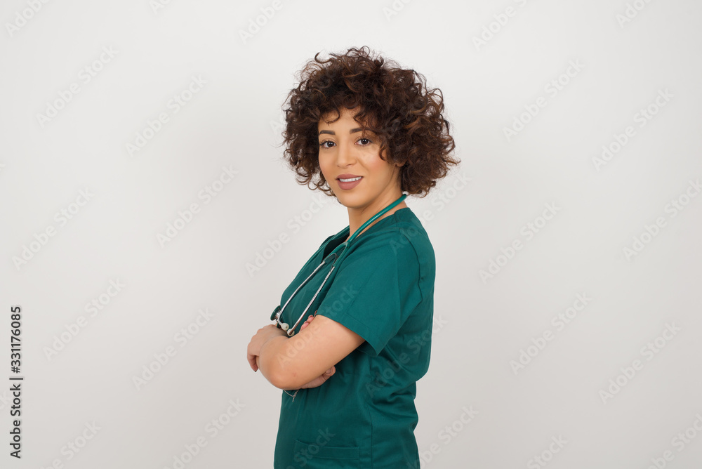 Image of cheerful pretty caucasian doctor lady with arms crossed wearing medical uniform. Looking and smiling at the camera. Confident successful woman. Health concept. Image of cheerful pretty caucasian doctor lady with arms crossed wearing medical uniform. Looking and smiling at the camera. Confident successful woman. Health concept.