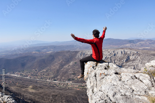 Man rise a hands on top of the mountain. Concept of freedom. Young man enjoy on a cliff edge