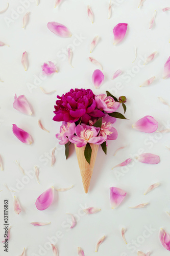 Fototapeta Naklejka Na Ścianę i Meble -  Ice cream cone with bouquet of bright pink peonies. Background of lot of pink petals. Spring or summer floral concept. Pink and violet blossom. Creative minimalism. Flat lay