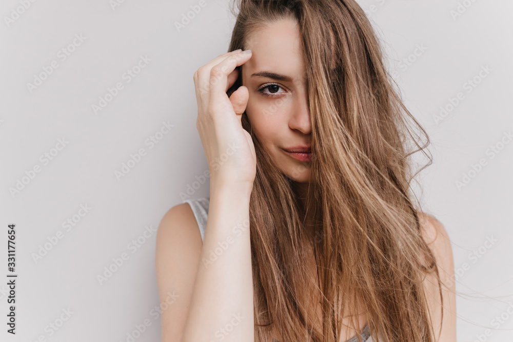 Gorgeous white girl posing with calm face expression. Indoor portrait of amazing female model with long hair isolated on light background. Gorgeous white girl posing with calm face expression. Indoor portrait of amazing female model with long hair isolated on light background.