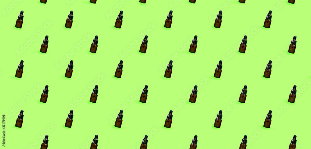 Pattern of herbal oil bottle aroma dropper on green mint color background.