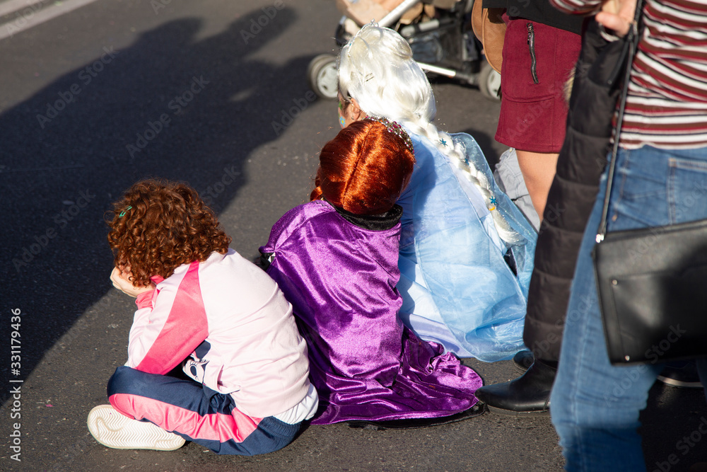 Fototapeta premium Three tired kids on a carnival feast, wearing carnival costumes