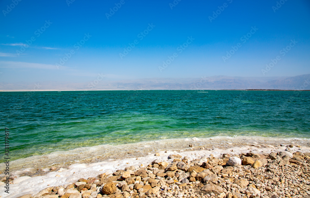 The clear water with concentrated saltof the Dead Sea overlooking the mountains of Jordan
