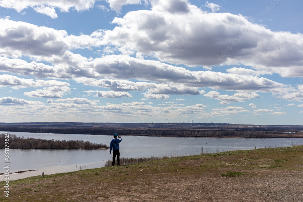 Boy taking photo of river and beautiful sky