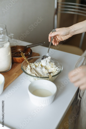 female hand prevents a golden.fork with a white cup on a white table cottage cheese in a cup