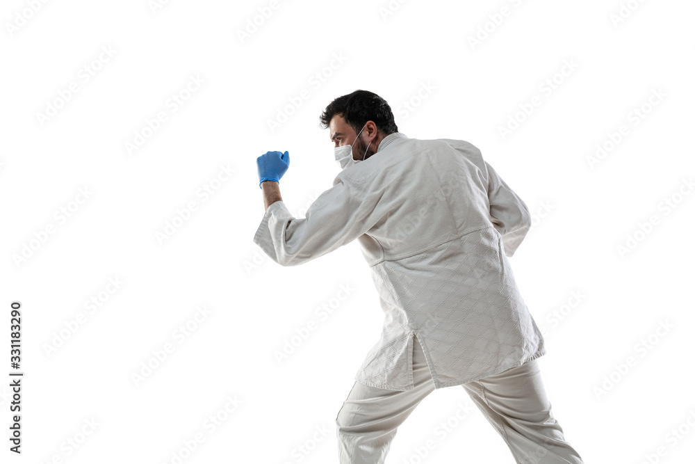 Punching virus. Martial arts fighter in protective mask and gloves. Prevention against pneumonia. Still active while quarantine. Chinese coronavirus treatment. Healthcare, medicine, sport concept. Punching virus. Martial arts fighter in protective mask and gloves. Prevention against pneumonia. Still active while quarantine. Chinese coronavirus treatment. Healthcare, medicine, sport concept.